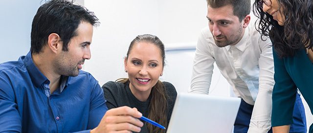 Four business professionals collaborating around a laptop in a bright office meeting room ID 248801416 by NicoElNino | Adobe Stock